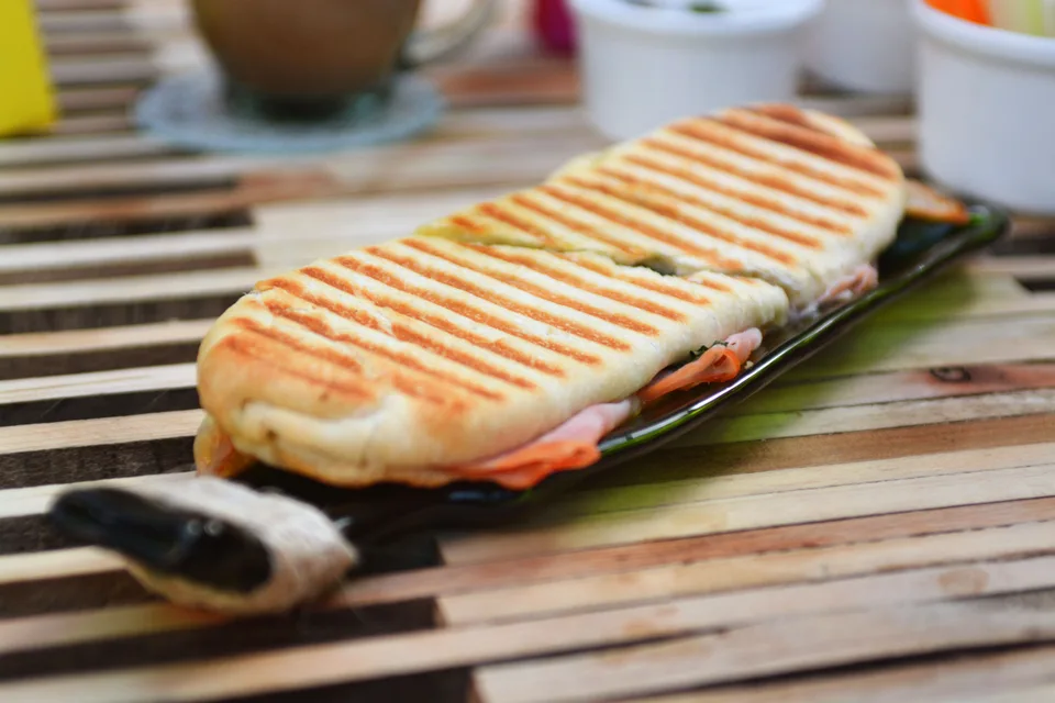 BookNoFees: Iliustracinė nuotrauka: Skrudintas paninis su grotelių žymėmis tamsioje lėkštėje